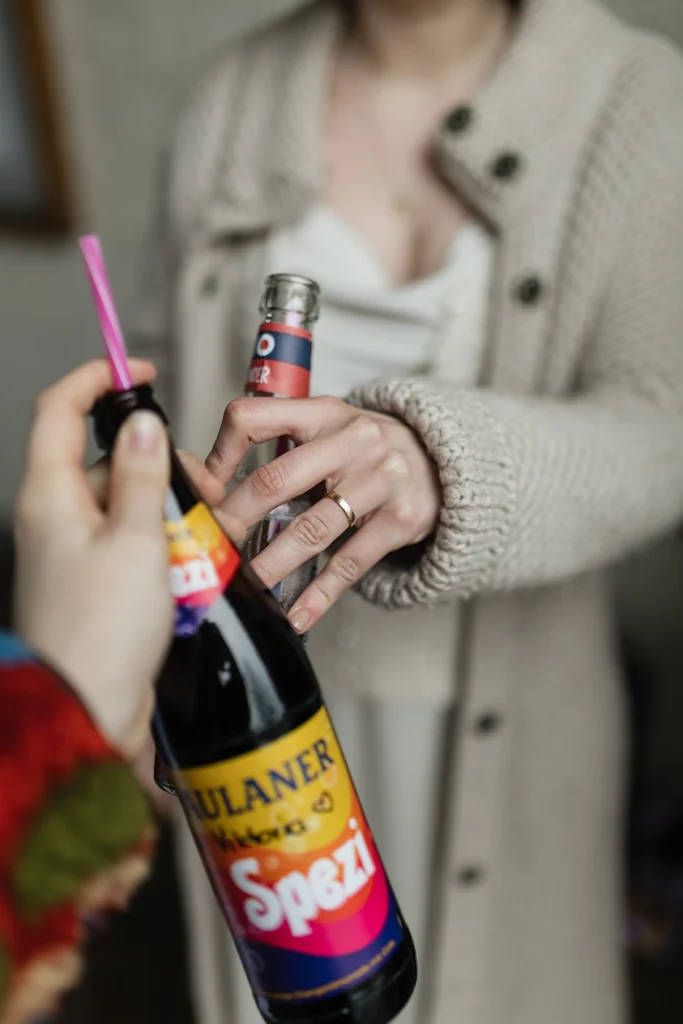 Braut stoßt mit einer Paulaner Spezi an. Fokus auf ihrem Ehering